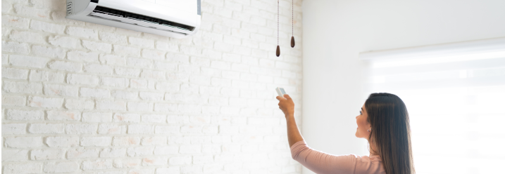 Person bedient Klimaanlage mit Fernbedienung